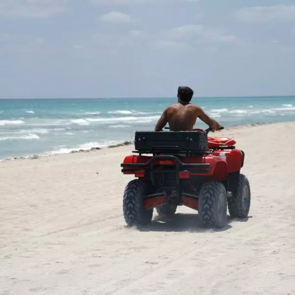 A man riding an ATV on Atlantis Beach, enjoying the thrill of the ride amidst the sandy shores.