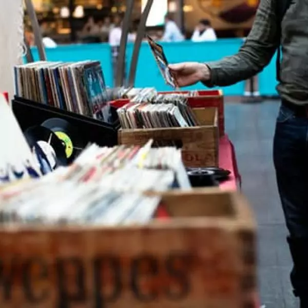 A man browsing records at a flea market, with 'atlantist two rocks' in the background.