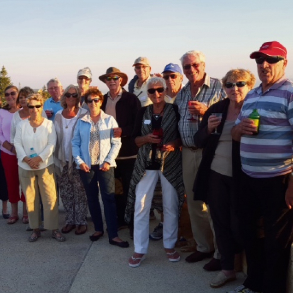 A group of people standing together on a hillside overlooking atlantist two rocks.