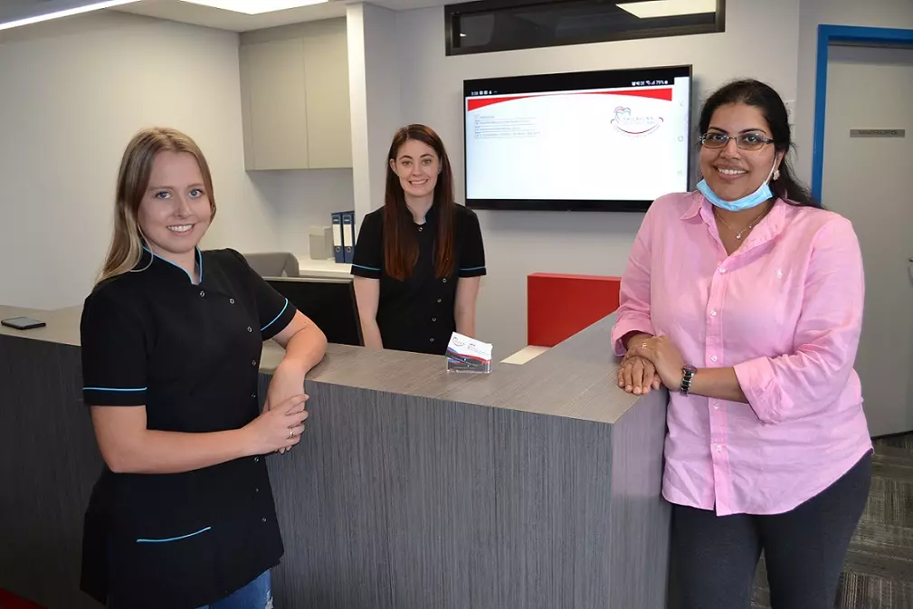 Three Women At Atlantis Reception Desk With Two Rocks In Background.